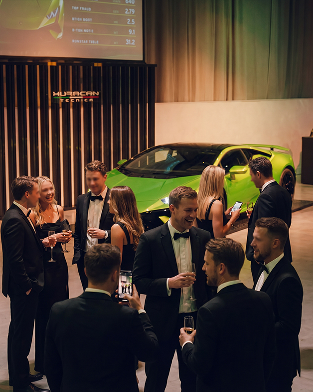 Black-tie guests mingling in front of a green Lamborghini Huracán Tecnica at the launch event